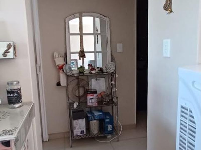 A functional hallway featuring neutral tiled flooring and a classic archway leading into the adjacent living space.