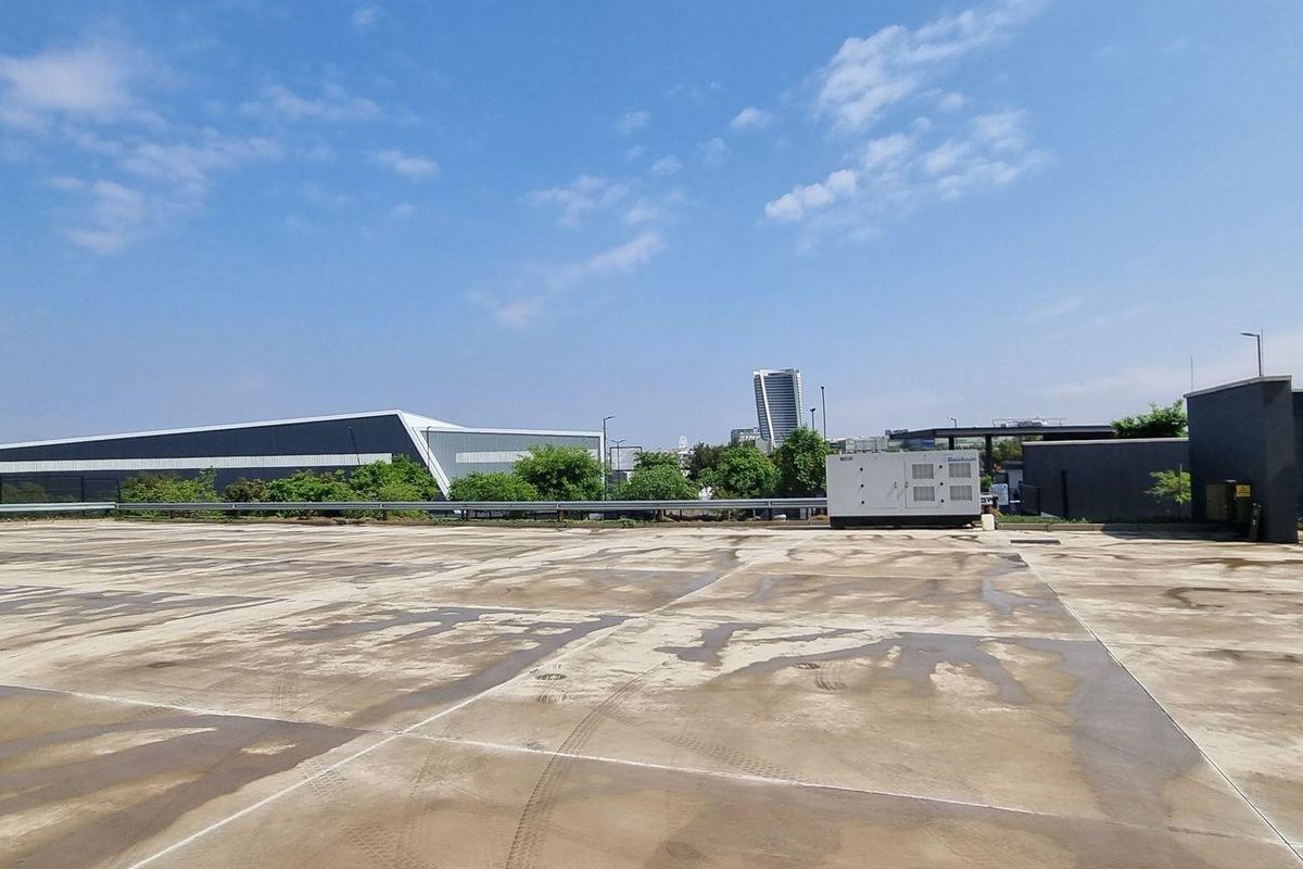 Expansive industrial rooftop parking or utility area with concrete surfacing and perimeter fencing, offering clear views of the surrounding industrial precinct.