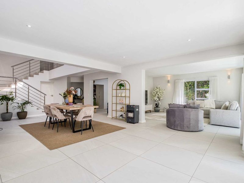 Spacious open-plan living and dining area featuring modern tiled flooring, recessed lighting, and a contemporary staircase with a stainless steel balustrade.