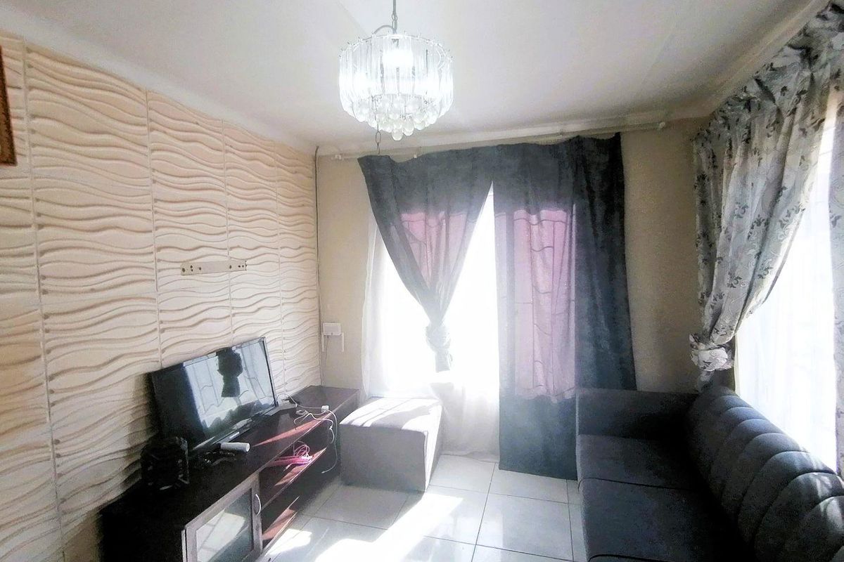 A living room featuring tiled flooring, a textured feature wall, and a decorative crystal chandelier.