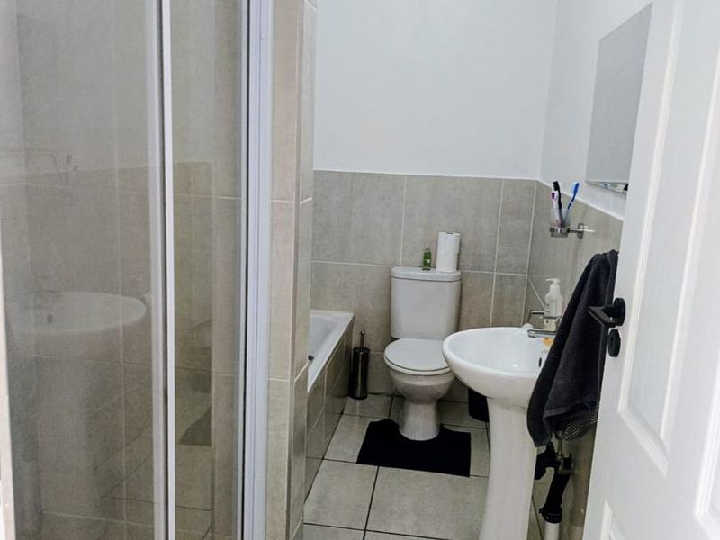 A functional bathroom featuring a shower enclosure, pedestal basin, toilet, and bathtub with neutral tiled finishes.