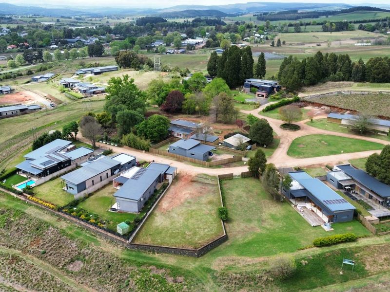 An aerial view of a residential estate featuring modern homes, landscaped gardens, and established infrastructure within a scenic rural landscape.