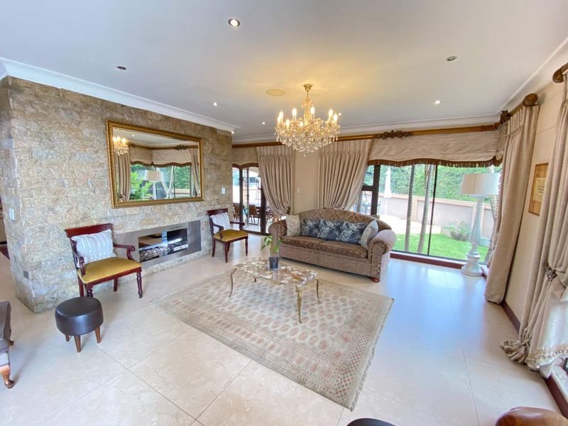 Spacious living room featuring a stone accent wall with a built-in fireplace, large sliding glass doors, and polished tile flooring.