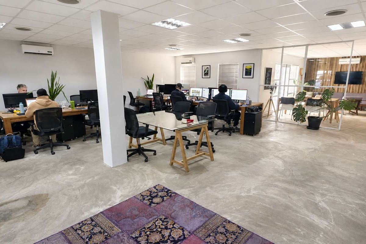 Open-plan office space featuring polished concrete floors, suspended ceilings with recessed lighting, and a glass-partitioned meeting area.
