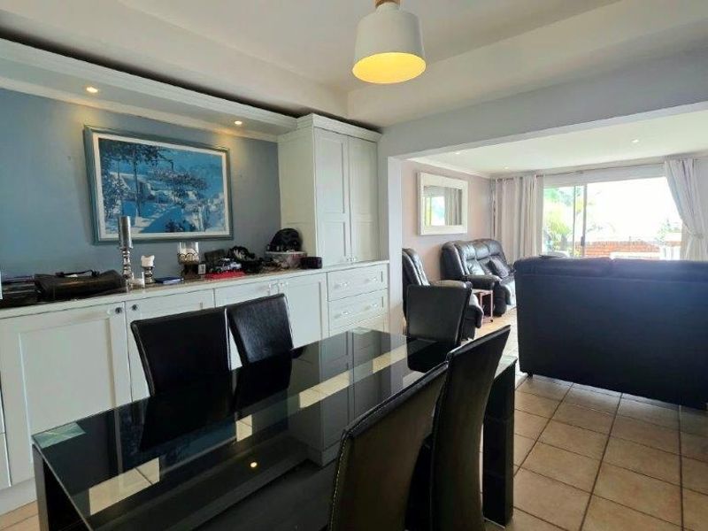 Open-plan living and dining area featuring built-in cabinetry, tiled flooring, and a sliding glass door leading to an outdoor space.