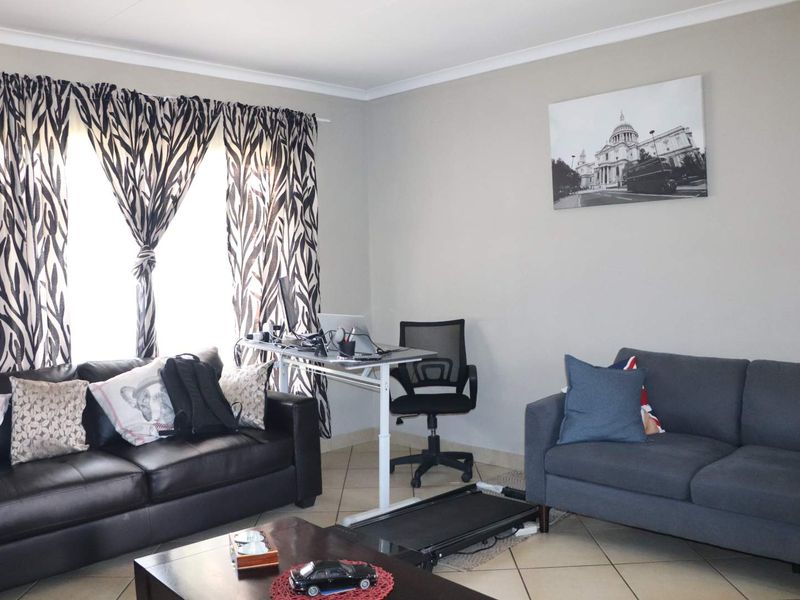 A functional living room space featuring neutral wall tones, tiled flooring, and coved ceiling details, offering a versatile area for relaxation or home office use.