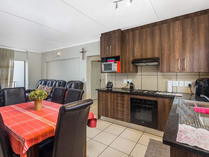 Open-plan living and dining area featuring a modern kitchen with dark wood cabinetry, granite countertops, and integrated appliances.