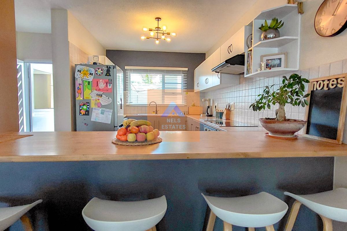 A functional kitchen featuring a breakfast bar, tiled backsplash, built-in cabinetry, and an extractor fan, offering a practical layout for daily cooking.