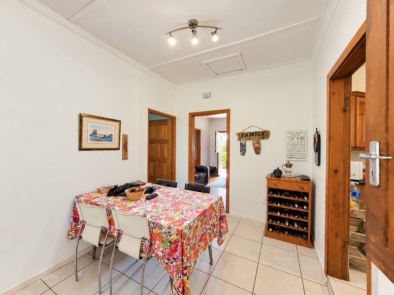 A functional dining area featuring tiled flooring, neutral walls, and direct access to adjacent rooms through timber-framed doorways.