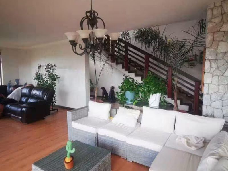 Spacious living area featuring a stone fireplace, timber staircase with wooden handrail, and laminate flooring, creating a warm and inviting atmosphere.