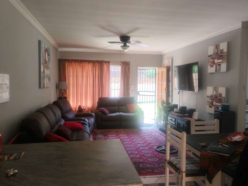 Open plan living area featuring tiled flooring, a ceiling fan, and direct access to the exterior through a security gate.