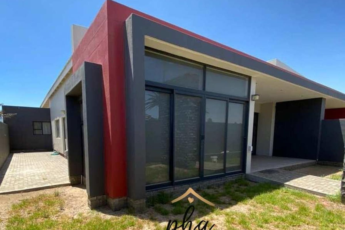 Modern exterior rear view of the house featuring a covered patio, large sliding glass doors, and paved outdoor areas.