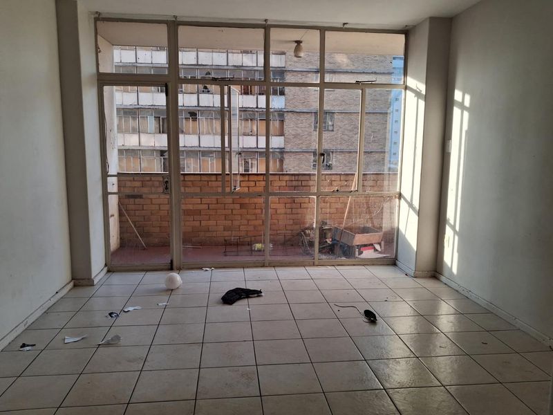 An empty living area featuring tiled flooring and large glass doors leading to an outdoor balcony space.