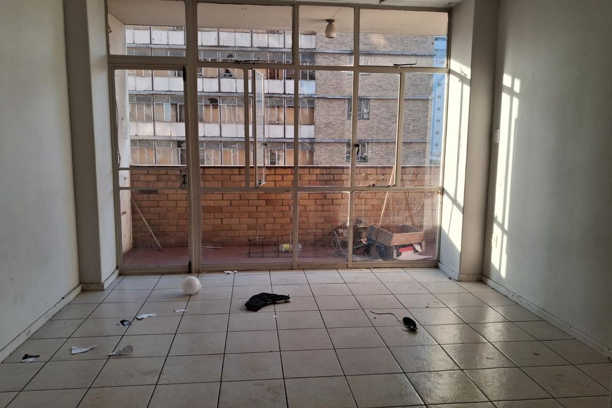 An empty living area featuring tiled flooring and large glass doors leading to an outdoor balcony space.
