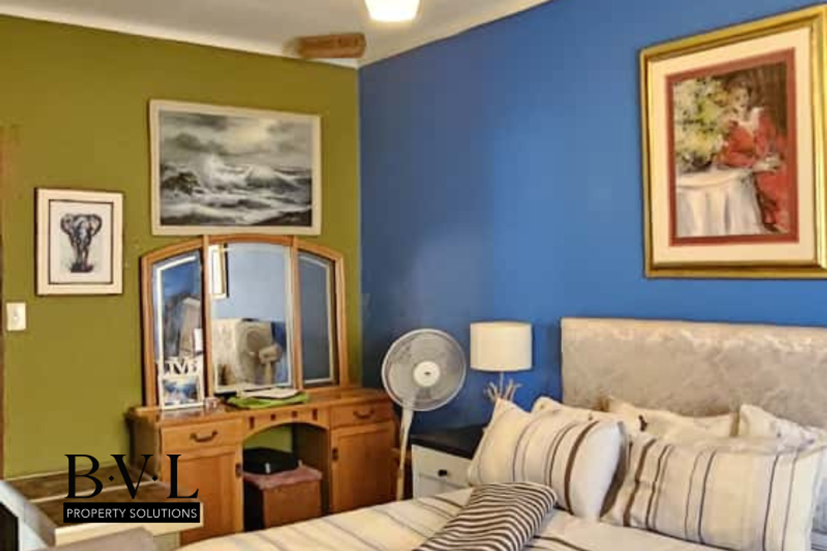 A bedroom featuring a dual-tone wall finish with a built-in vanity unit and integrated mirror.