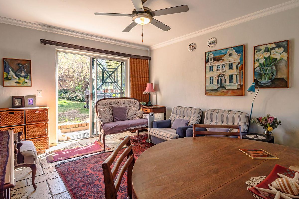 A living room featuring tiled flooring, a ceiling fan, and a sliding glass door providing direct access to the garden area.