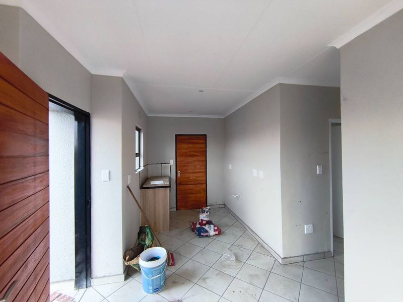 An empty kitchen area featuring tiled flooring, neutral wall paint, and basic built-in cabinetry, ready for final finishes or staging.
