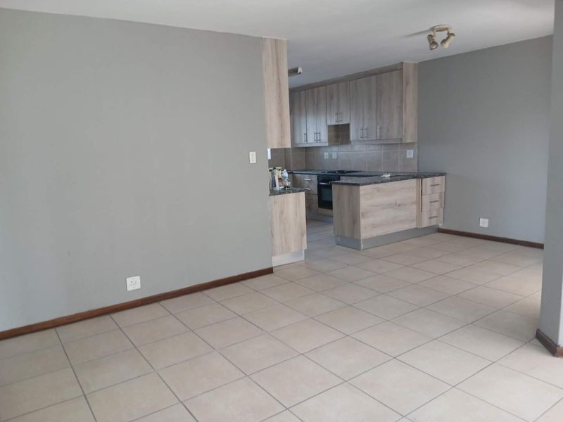 Open plan living area featuring tiled flooring and a functional kitchen with built-in cabinetry, granite countertops, and integrated oven and hob.