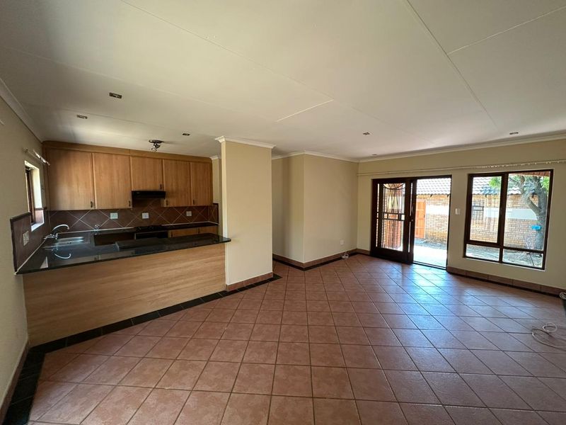 Spacious open-plan living area featuring a functional kitchen with granite countertops, tiled flooring, and direct access to the rear exterior through a sliding door.