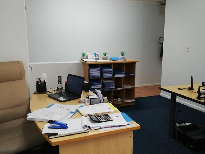 A functional office space featuring carpeted flooring and overhead fluorescent lighting, suitable for professional work environments.