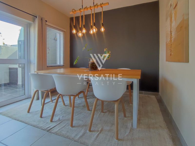A bright dining area featuring modern pendant lighting, tiled flooring, and a sliding glass door providing access to the exterior.