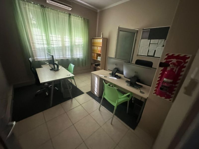 A functional office space featuring tiled flooring, an integrated air conditioning unit, and a wall-mounted fire extinguisher.