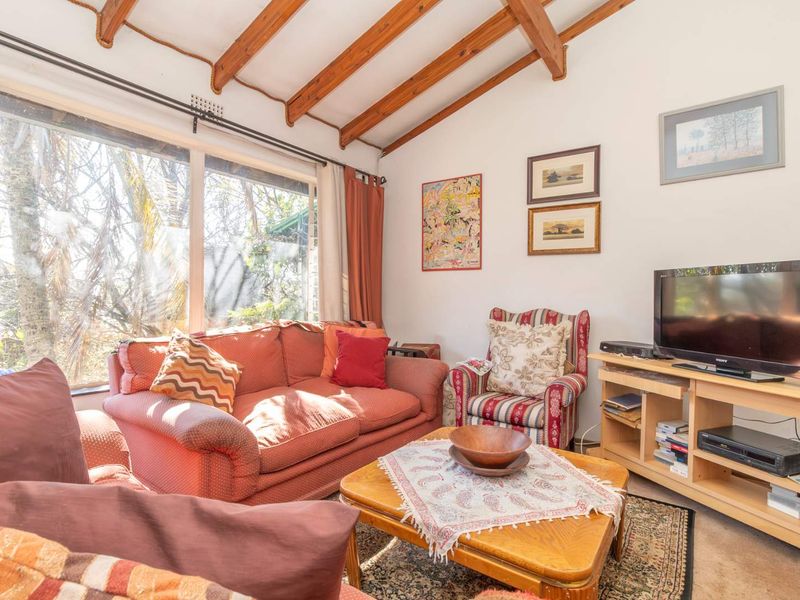 A cozy living room featuring exposed timber ceiling beams and a large window that provides ample natural light.