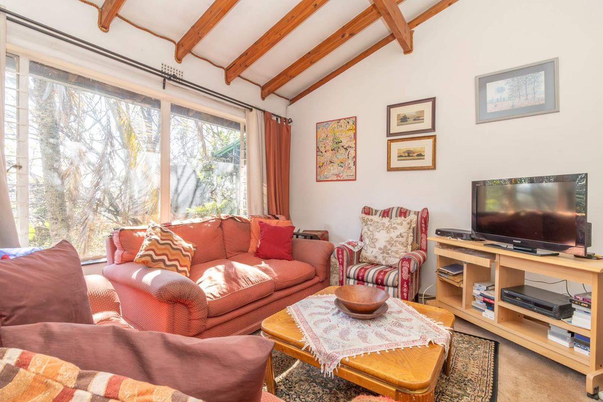 A cozy living room featuring exposed timber ceiling beams and a large window that provides ample natural light.