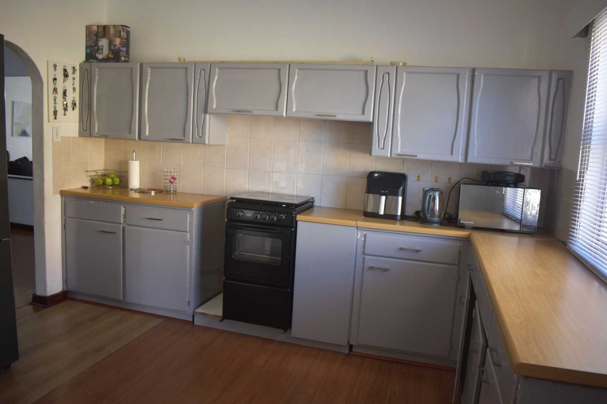 A functional kitchen featuring grey cabinetry, light wood-look countertops, and a freestanding oven, providing a practical workspace with neutral finishes.