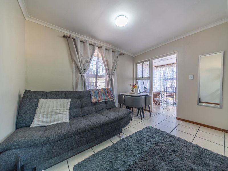 A living room area featuring tiled flooring, coved ceilings, and a sliding glass door leading to an adjacent sunroom or patio space.