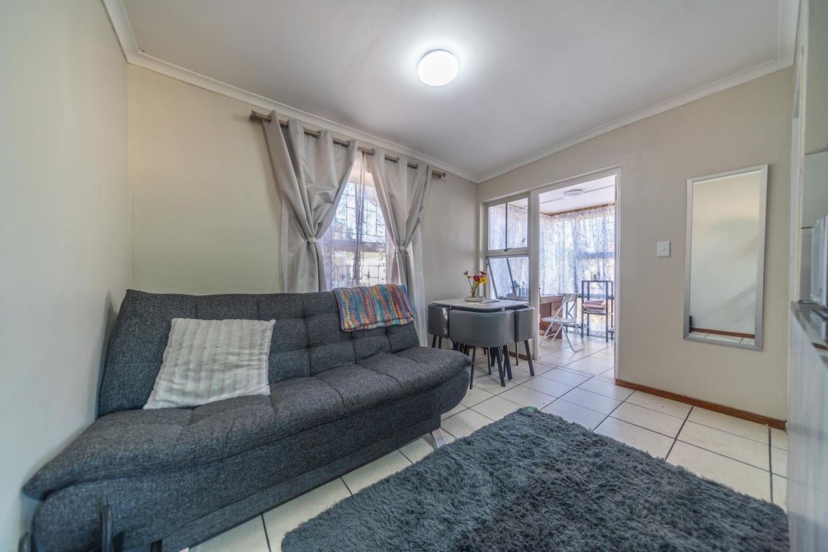A living room area featuring tiled flooring, coved ceilings, and a sliding glass door leading to an adjacent sunroom or patio space.