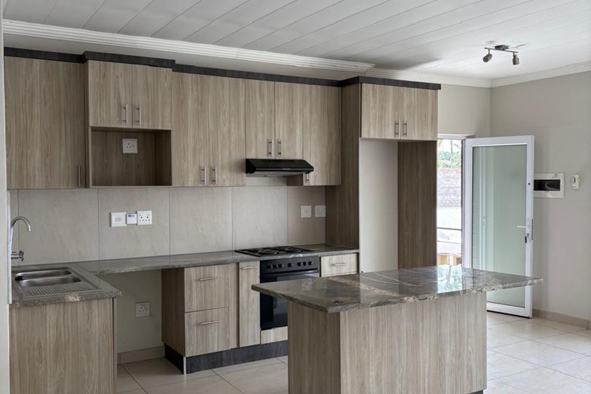 Modern kitchen featuring wood-grain cabinetry, stone-look countertops, a central island, built-in oven, extractor fan, and tiled flooring.