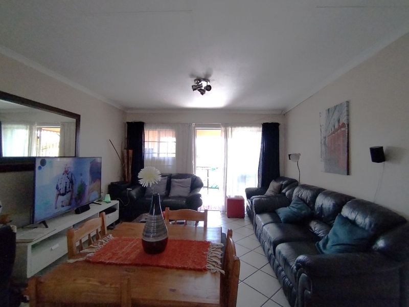 An open-plan living and dining area featuring tiled flooring and a sliding glass door leading to an outdoor space.