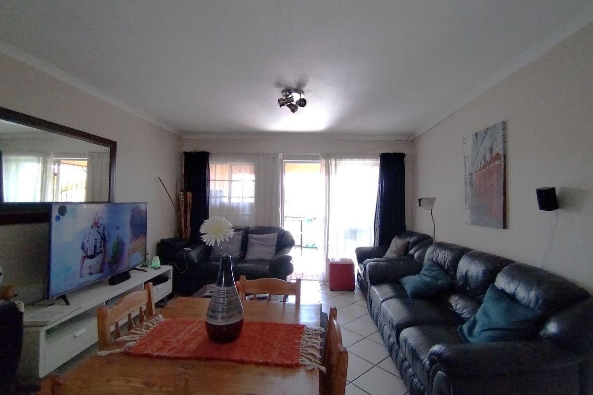 An open-plan living and dining area featuring tiled flooring and a sliding glass door leading to an outdoor space.