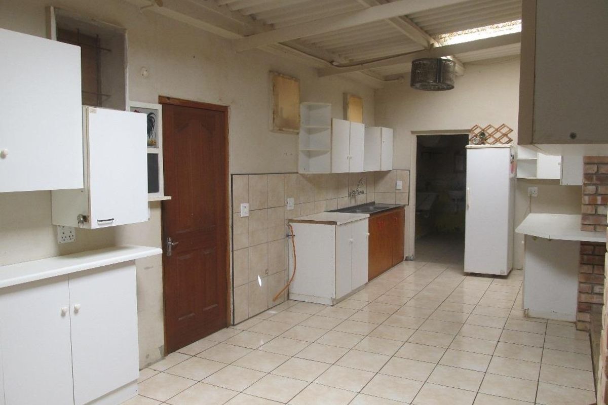A functional kitchen space featuring tiled flooring, built-in cabinetry, and a sink, offering a blank canvas for renovation and modernization.