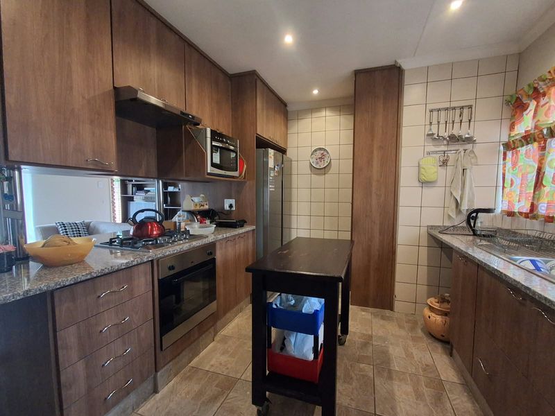 Functional kitchen featuring wood-finish cabinetry, granite countertops, built-in oven, gas hob, and tiled splashbacks, offering a practical layout for daily cooking.
