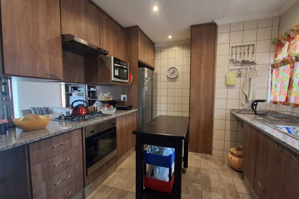 Functional kitchen featuring wood-finish cabinetry, granite countertops, built-in oven, gas hob, and tiled splashbacks, offering a practical layout for daily cooking.
