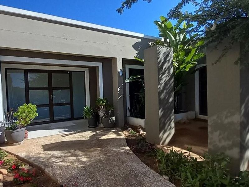 Modern front entrance featuring a paved walkway, concrete pillars, and a contemporary glass-paneled front door.