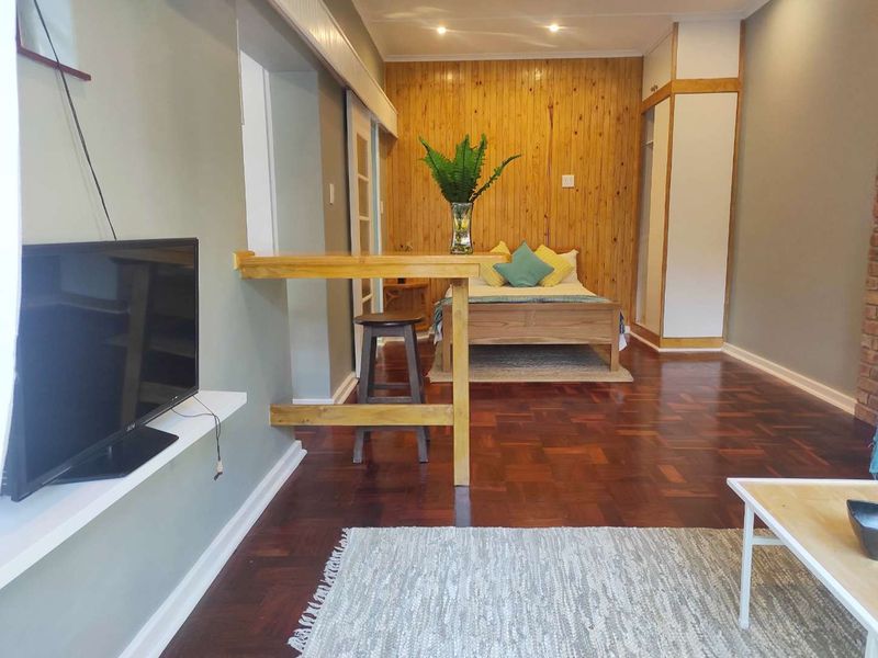 A cozy bedroom featuring warm timber wall paneling, polished parquet flooring, and a built-in cupboard, creating a comfortable and inviting living space.
