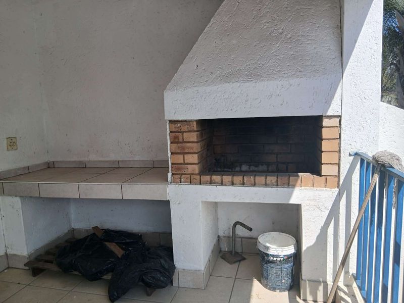 Outdoor patio area featuring a built-in brick braai and tiled preparation counter, providing a functional space for outdoor cooking and entertainment.
