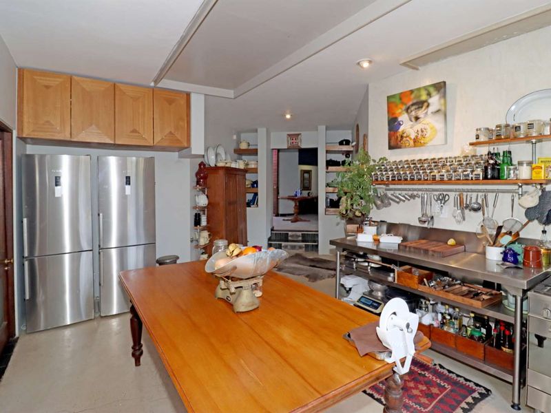 A functional kitchen featuring stainless steel work surfaces, built-in oven, gas cooktop, and ample wall-mounted storage shelving.
