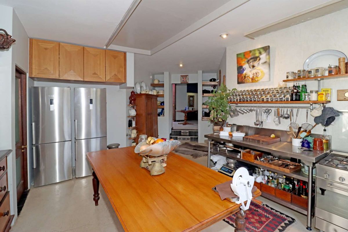 A functional kitchen featuring stainless steel work surfaces, built-in oven, gas cooktop, and ample wall-mounted storage shelving.