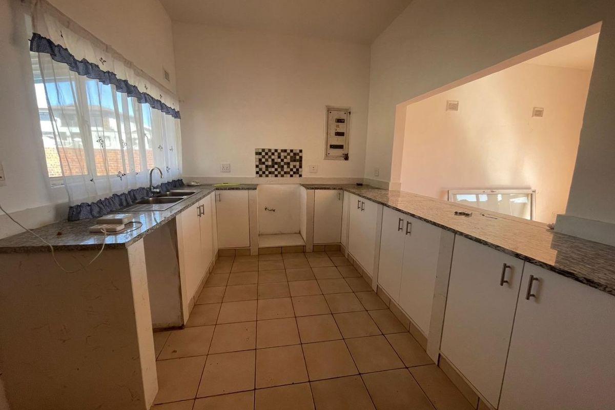 A functional kitchen space featuring granite countertops, double sink, and ample built-in cabinetry, ready for appliance installation and cosmetic updates.