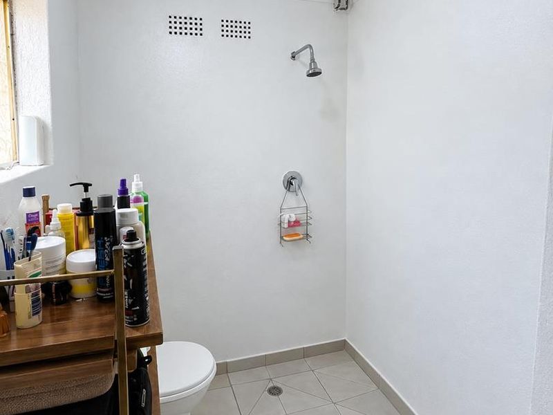 A functional bathroom featuring a walk-in shower area, toilet, and tiled flooring. The space requires minor ceiling repairs.