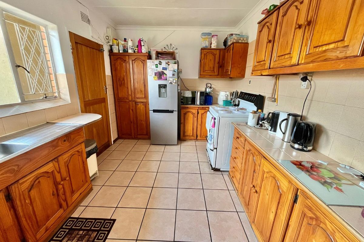 A functional kitchen featuring traditional wooden cabinetry, tiled flooring, and a built-in sink area with ample counter space.