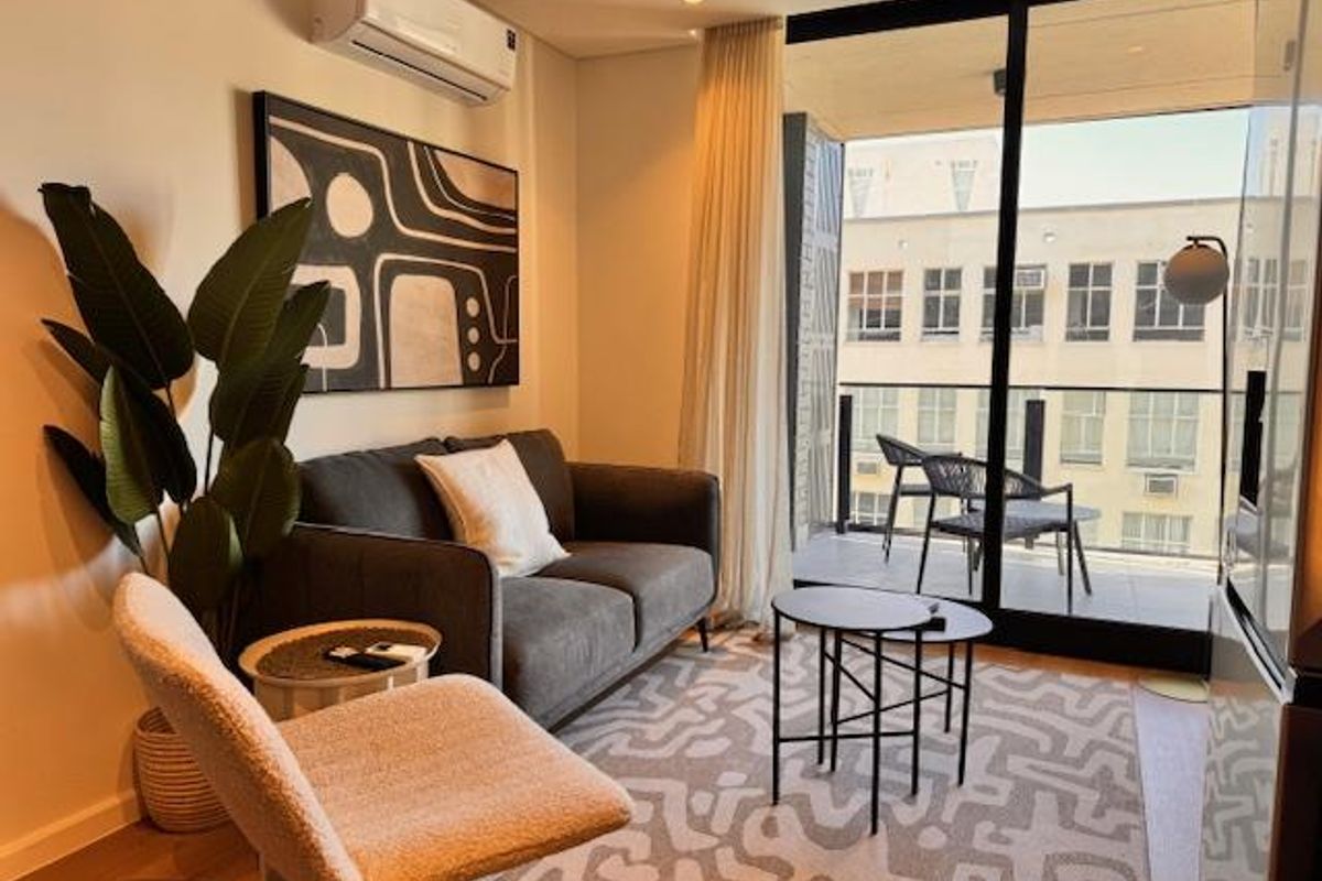 A cozy living room featuring a wall-mounted air conditioning unit and large sliding glass doors that open onto a private balcony.
