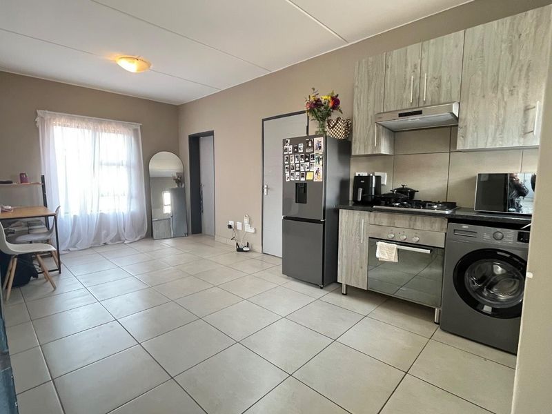 Open-plan living area featuring a functional kitchen with built-in cabinetry, gas hob, oven, and tiled flooring throughout.