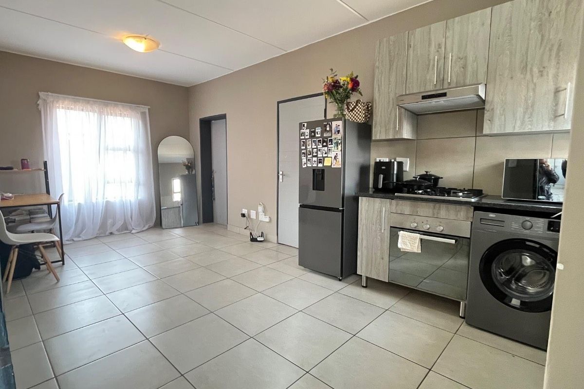 Open-plan living area featuring a functional kitchen with built-in cabinetry, gas hob, oven, and tiled flooring throughout.