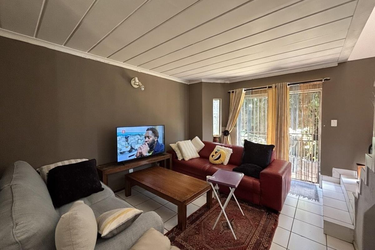A living room featuring tiled flooring, a panelled ceiling, and sliding glass doors leading to an outdoor area.