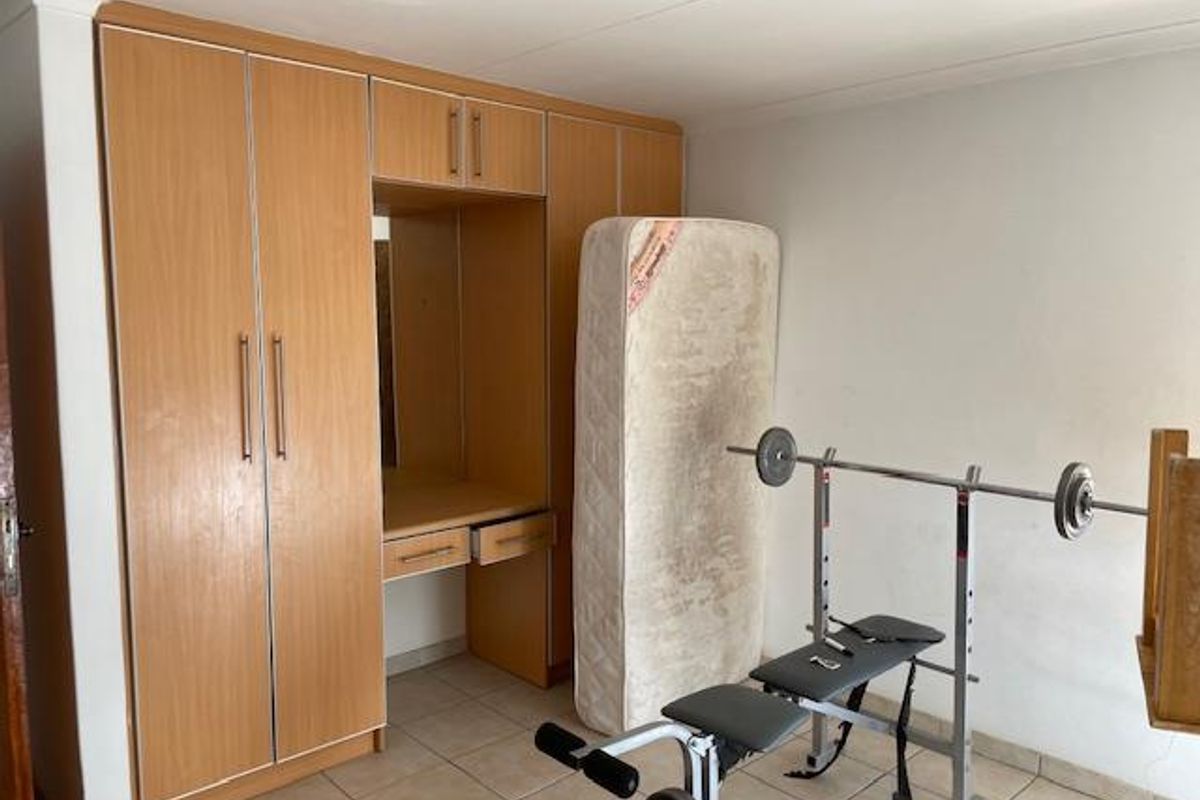 Bedroom featuring built-in wooden cabinetry with integrated vanity and tiled flooring.